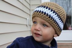 a young boy wearing a crocheted hat on top of his head in front of a house