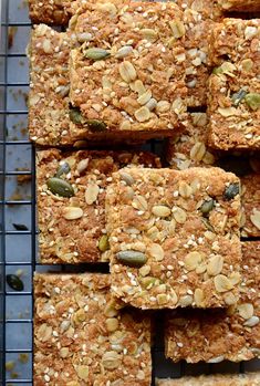 several squares of oatmeal bars on a cooling rack with nuts and seeds