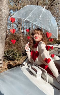 a woman sitting in the back of a car holding an umbrella over her head with hearts attached to it