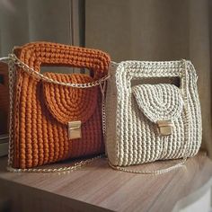 two purses sitting on top of a wooden table next to each other, one in orange and the other in white