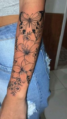 a woman's arm with flowers and butterflies tattooed on the side of her arm