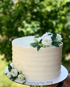 there is a white cake with flowers on the top and bottom layer, sitting on a plate