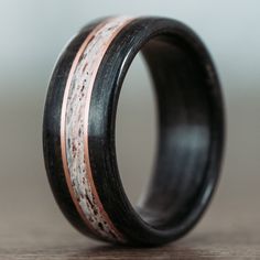 a black and white ring with copper inlays on the inside, sitting on a wooden surface