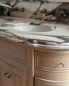 a bathroom vanity with marble counter top and wooden cabinetry on the bottom, along with two faucets