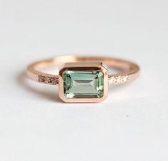 A solitaire emerald cut green tourmaline & pave diamond ring made in 18k gold, pictured in rose gold. Perfect as a unique engagement or wedding large gemstone ring.
The design can be made with gemstones of your choosing. If you would prefer a custom ring, please contact us before purchase.
Details Main Stone: green/mint tourmaline Shape: emerald cut Measurements: approx. 7.5x5 - 8x5mm Tourmalines are natural therefore they might slightly vary in color from the depicted one.
Side stones: white di Rose Gold Emerald Cut Emerald Ring, Rose Gold Ring Simple, Tourmaline Engagement Ring, Rose Gold Plated Ring, Green Tourmaline Ring, Emerald Cut Rings, Pave Diamond Ring, Rose Engagement Ring, Rose Gold Engagement