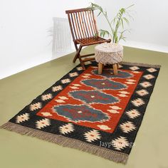 a wooden chair sitting on top of a green floor next to a black and red rug