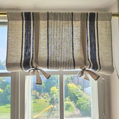 a window with two bow ties hanging from it's valance, in front of a large window