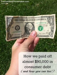 a person holding up a one dollar bill in their left hand on the green grass