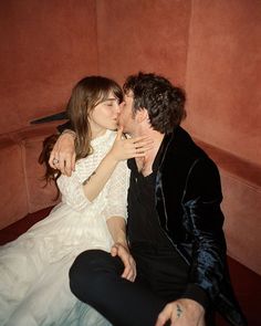 a man kissing a woman on the cheek in front of a red wall and floor