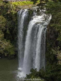 a large waterfall with water cascading over it's sides in the forest