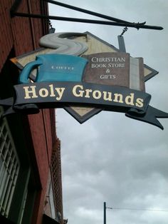 a sign for a coffee shop hanging from the side of a building on a cloudy day