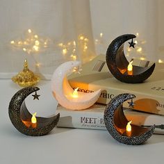 three moon shaped candles sitting on top of a book next to a stack of books