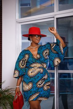 A woman posing in a blue and tan African print mini dress. She is pictured from the waist up and smiling. She is styled with a red beaded purse Afro Design, Hebrew Women, Wimbledon Fashion, African Print Dress Designs, Stylish Work Attire, Ankara Print, African Ankara, Classy Design, Design Dresses