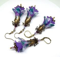 Purple earrings, Art Nouveau earrings, flower earrings. Hand painted and color sealed purple flower earrings with a splash of lilac purple, ivory and cyan turquoise accompanied by a purple mini-inner flowers and a wonderful collaboration of antique bronze elements and findings with grape purple and lilac purple and metallic purple faceted crystal accent beads. Dressed up or down these colorful floral earrings are sure to compliment you. Earrings are lightweight and can be worn comfortably all da Artistic Purple Earrings For Gift, Unique Purple Earrings With Ear Wire, Artistic Purple Jewelry With Matching Earrings, Artistic Hand-painted Purple Earrings, Lavender Flower-shaped Earrings For Gifts, Purple Flower-shaped Whimsical Jewelry, Whimsical Purple Flower Jewelry, Artistic Purple Dangle Earrings, Whimsical Purple Flower-shaped Jewelry