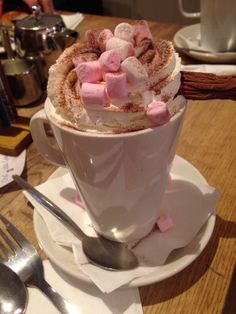 a cup filled with hot chocolate and marshmallows on top of a saucer