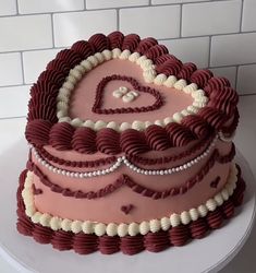 a heart shaped cake on a plate with white and red icing in the middle