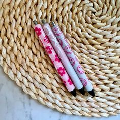 two pens sitting on top of a wicker basket next to another pen with pink and white designs