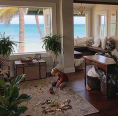 a young boy playing with toys in a living room next to a window overlooking the ocean