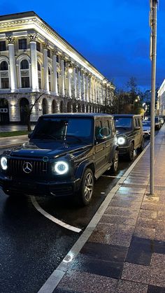 two cars parked on the side of the road in front of a building at night