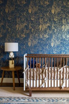 a baby's crib in front of a blue wall with gold foiling