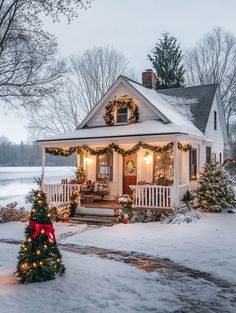 a small white house decorated for christmas with wreaths and lights on the front porch