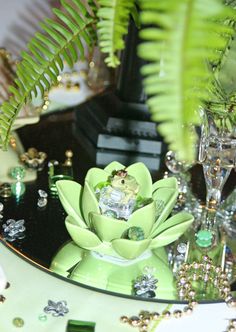 a table topped with green plants and glass vases