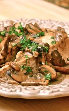 a white plate topped with mushrooms and gravy on top of a wooden table