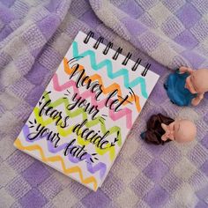 two small figurines sitting next to a notebook