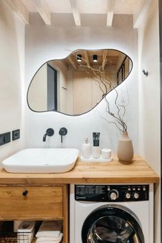 a washer and dryer in a bathroom with a large mirror above the sink