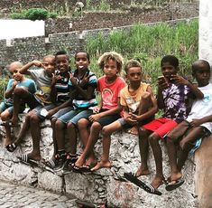 a group of children sitting on top of a stone wall