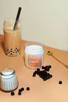 a candle and some blackberries on a table next to a jar of liquid with a spoon in it