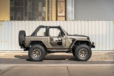 the jeep is parked on the side of the road in front of an industrial building