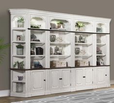 a large white bookcase with glass doors and shelves on each side, in a living room