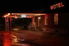 the motel is lit up at night with red lights on it's front entrance