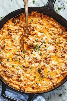 a skillet filled with cheesy ground beef casserole on a marble surface