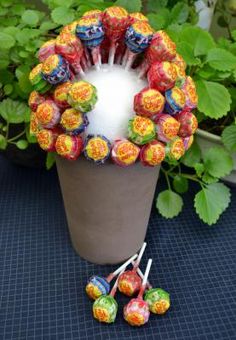 an arrangement of candy candies in a flower pot on a table next to some plants