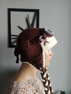 a woman wearing a crocheted hat with braids and a button on the side