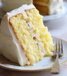 a slice of yellow cake on a plate with a fork and knife next to it