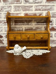 an old wooden bench with drawers and lace on the floor next to it, in front of a brick wall