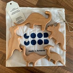 three wooden animals on a white cloth with tags hanging from it's sides and an ad for made in america