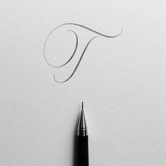 a fountain pen drawing the letter t on paper