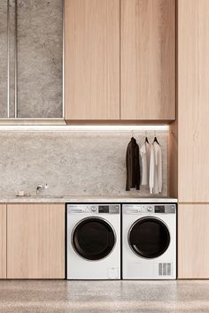 a washer and dryer are in the middle of a room with wooden cabinets