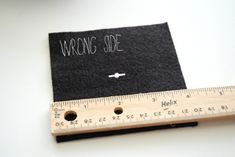 a wooden ruler with writing on it next to a black piece of cloth that says wrong side