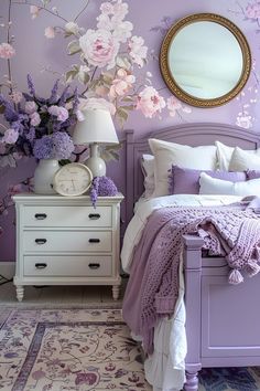 a bedroom decorated in lavender and white with flowers on the wall, bedding and dresser