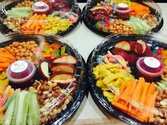 four plastic plates filled with different types of vegetables and meats on top of each other