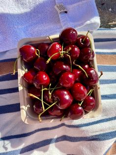 a bowl filled with lots of cherries on top of a towel