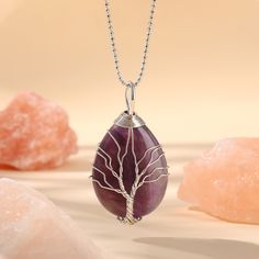 PLEASE NOTE: Our crystal stones are natural minerals and each crystal is unique. The internal ice cracks, pits, mineral points, and color differences of natural crystals are all formed naturally and are normal phenomena, which will not affect the efficacy, beauty and value of the crystal at all.This necklace is probably the most beautiful piece of jewelry you'll ever see. The intricate tree design weaved around the gorgeous purple crystal adds to this necklace's charm. Wear this magical piece ar Spiritual Gemstone Teardrop Pendant Crystal Necklaces, Spiritual Teardrop Gemstone Crystal Necklace, Crystal Pendant Necklace With Natural Stones, Silver Nature-inspired Crystal Necklace For Healing, Mineral Crystal Pendant Necklace For Healing, Mineral Crystal Pendant Necklaces For Healing, Nature-inspired Silver Crystal Necklace For Healing, Healing Large Stone Silver Crystal Necklace, Purple Rose Quartz Gemstone Jewelry