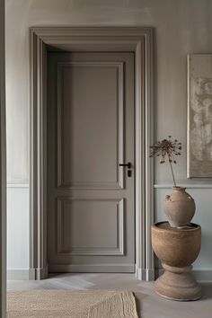 a vase with a flower in it sitting on the floor next to an open door