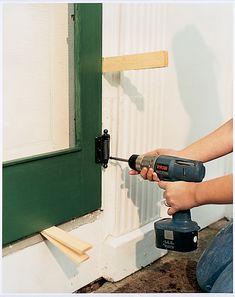 a person using a drill to fix a door