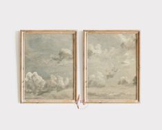 two paintings hanging on the wall next to each other with clouds in the sky behind them